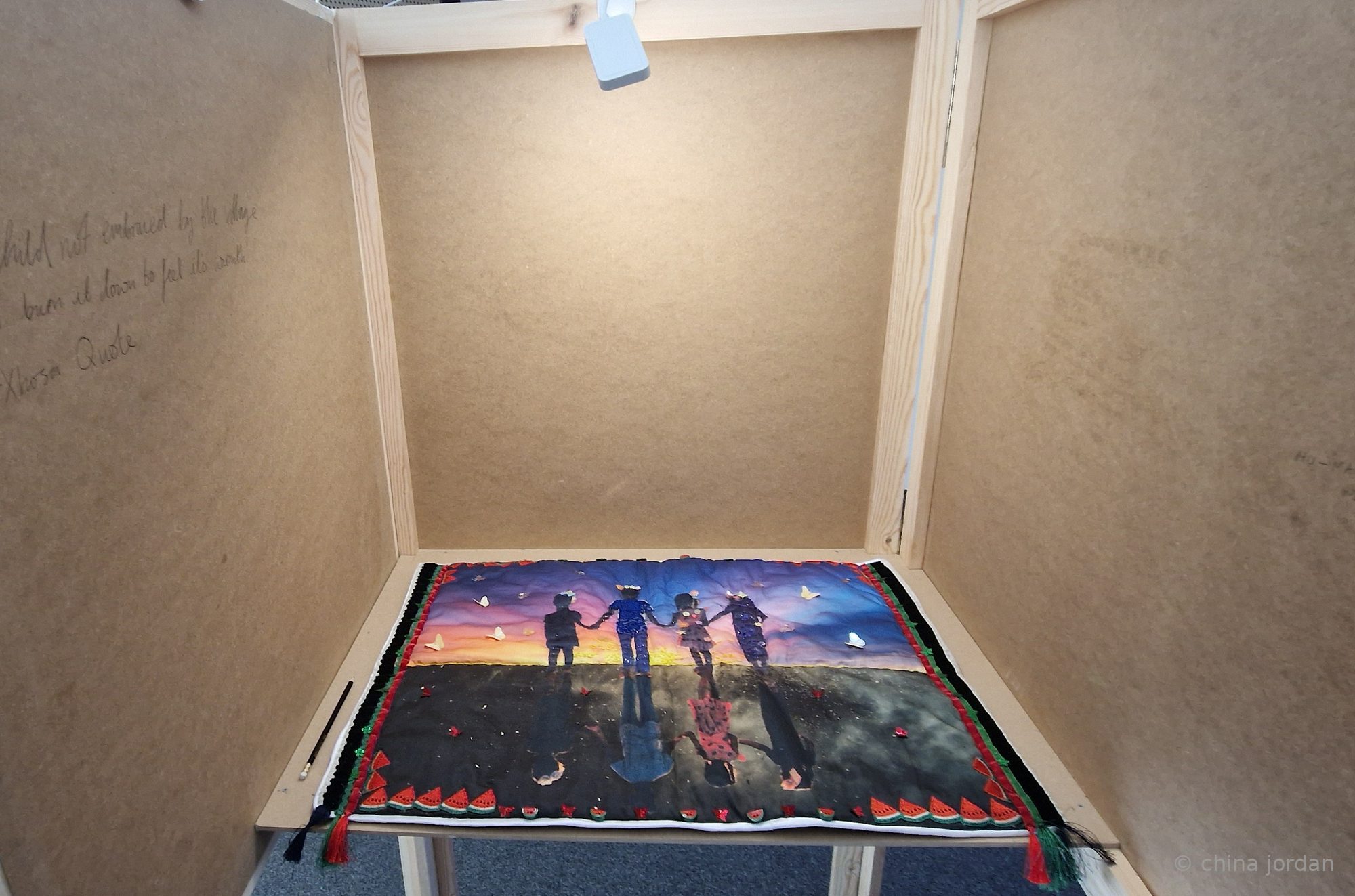 Between Us — booth interior with Care quilt and pencilled Xhosa proverb