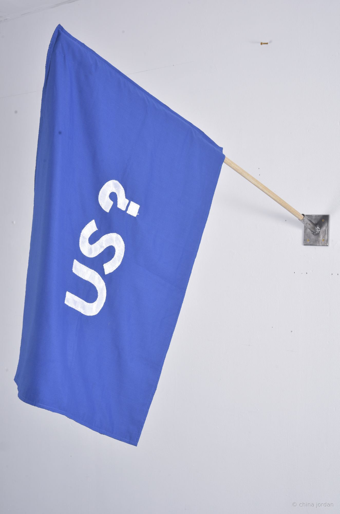 US? — appliqu&eacute;d blue fabric flag on wooden pole
